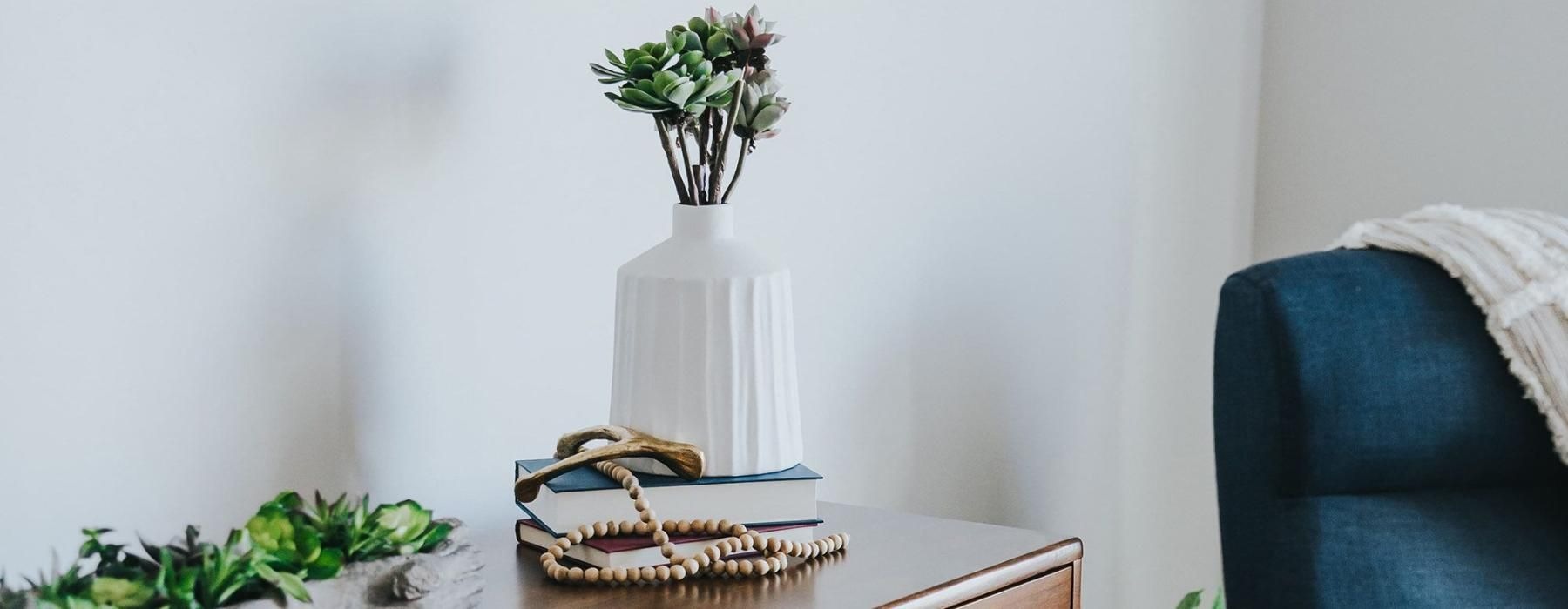 a dresser with a vase of plants on top